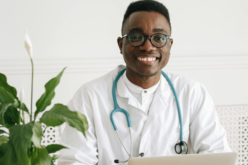 Cheerful young doctor in uniform with stethoscope and eyeglasses, exuding professionalism.